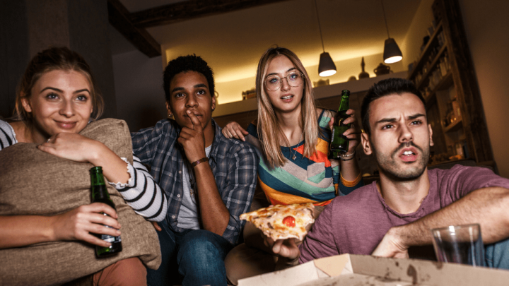 gruppe med fire personer som spiser, drikker og ser på tv